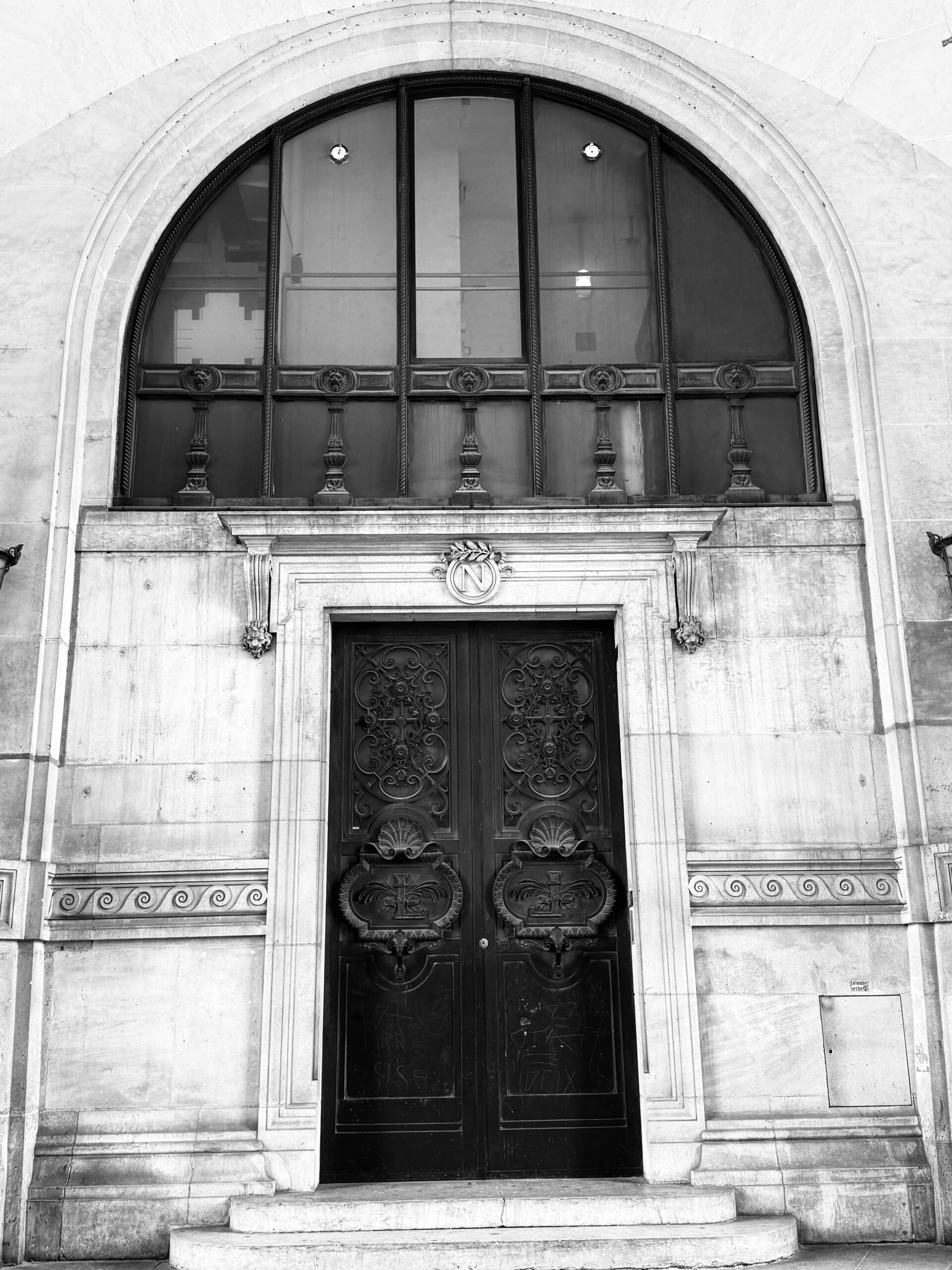 A black and white photograph of a grand, ornate door in Paris, used to illustrate the psychology of event entrances and first impressions by corporate magician and host Liam Ball.