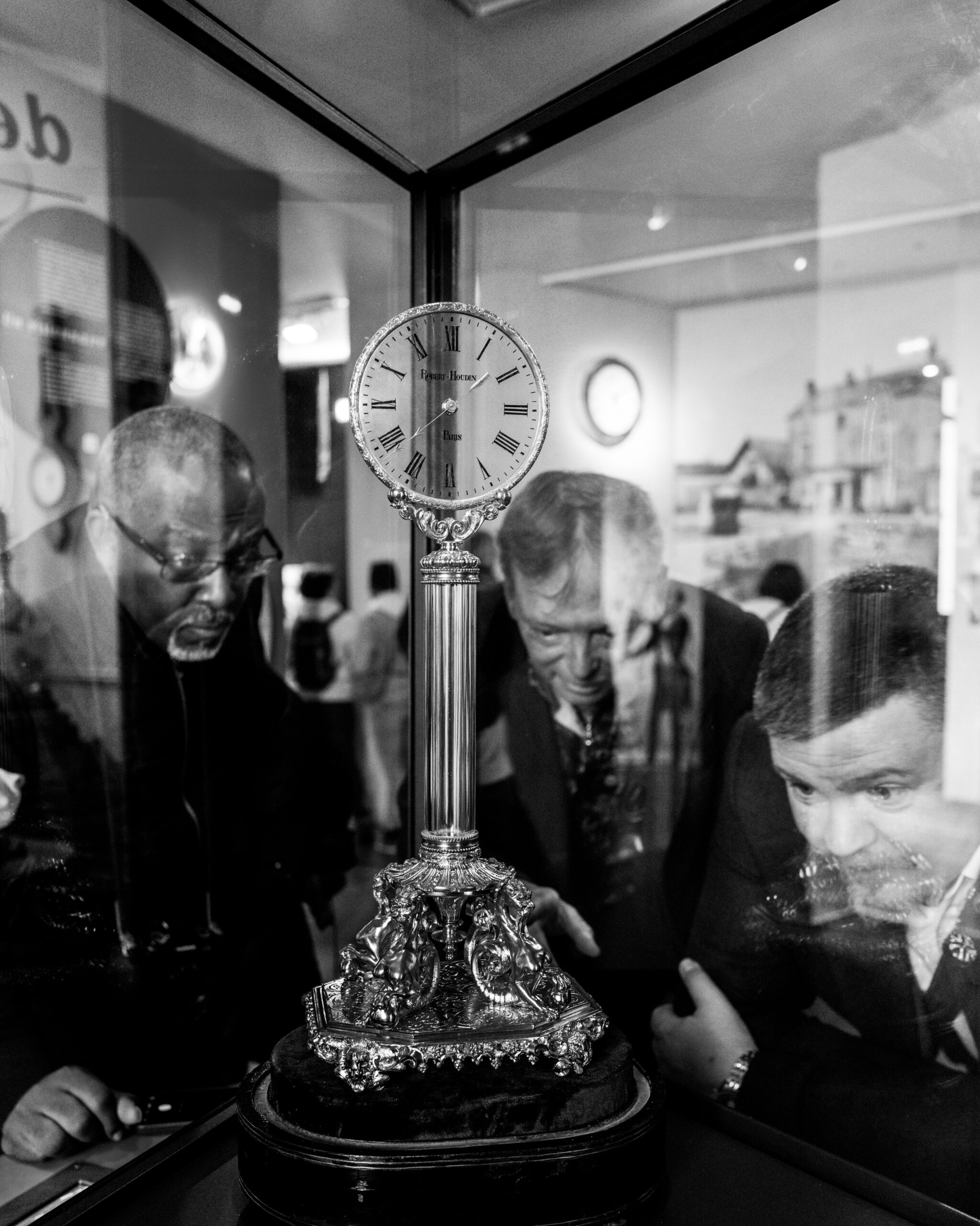 Corporate magician and host Liam Ball examining a historic Robert-Houdin mystery clock mechanism with performance experts in Paris, France.